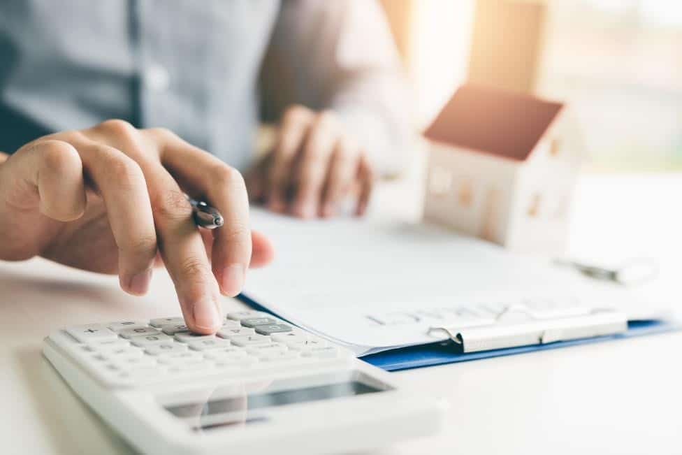 Person using calculator to discover if they should refinance their home.