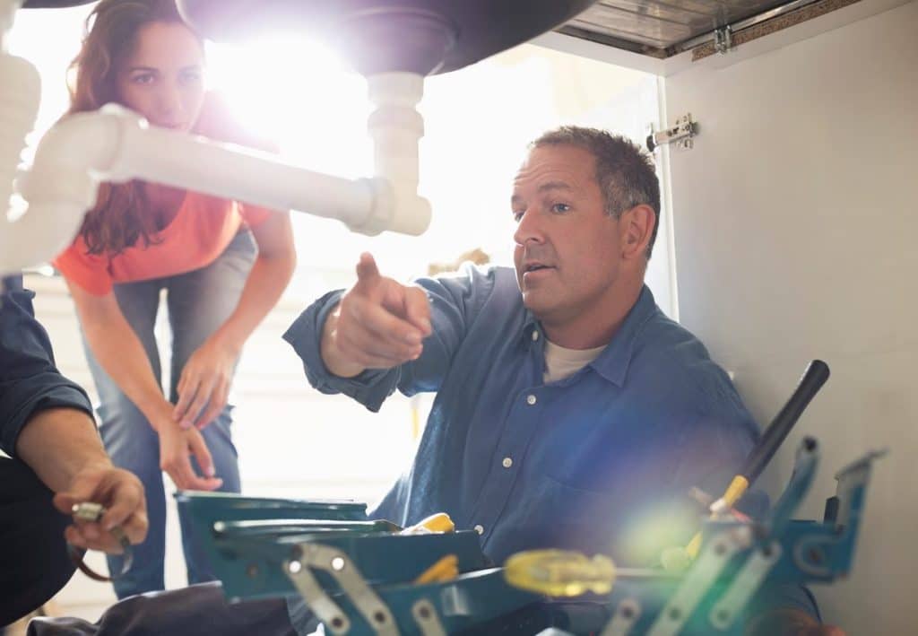 A plumber explains a plumbing issue to a homeowner