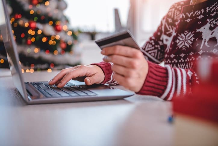 A person holding credit card while shopping online during the holiday season.