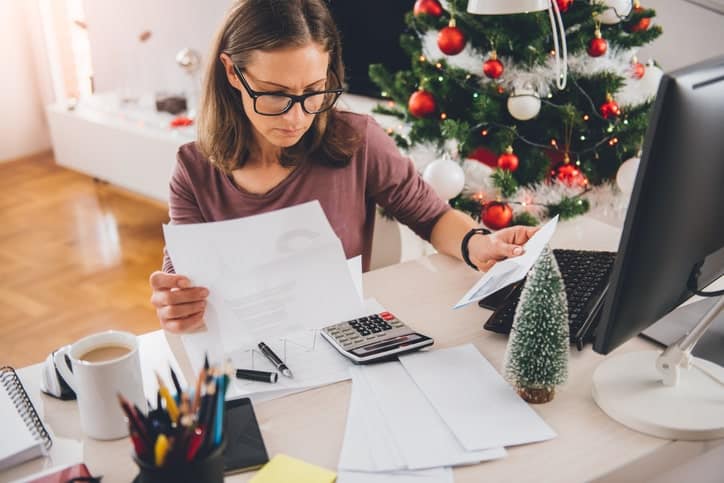 Woman sitting at a desk cluttered with bills.
