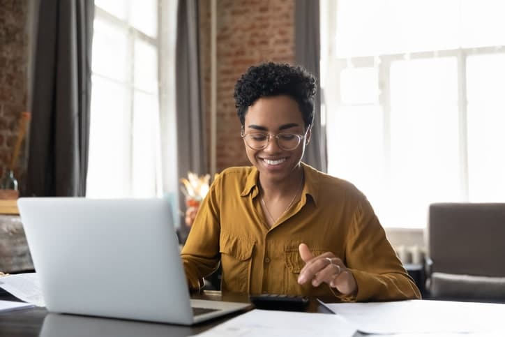 Young woman smiling and sitting at a laptop doing business taxes