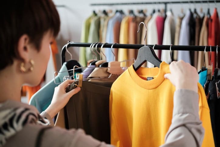 Woman looking at a yellow sweater on a rack.