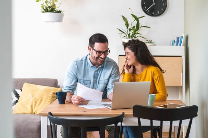 Couple sits at kitchen table, looking over documents.