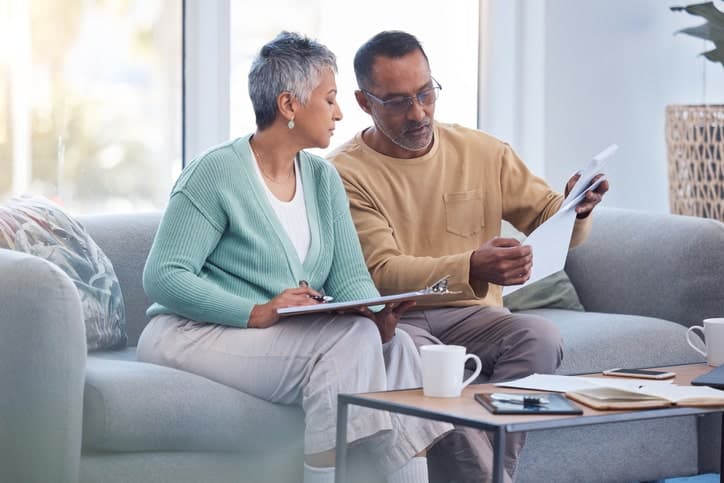 Mature couple looks over bills and documents together in their home.