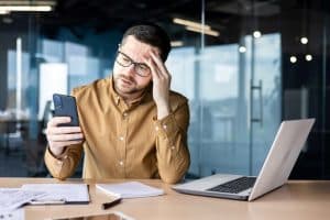 A man sits stressed over dealing with bank account fraud.