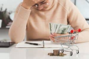 A young woman stressed about budgeting while holding money.