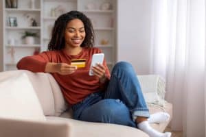 A woman uses her phone for online mobile banking from her home.